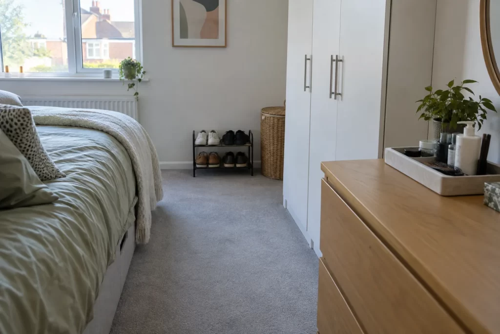 Clear bedroom walkway with shoes on a rack and toiletries grouped on a tray